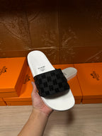 Hermes slide sandals held in hand, white footbed with black patterned strap