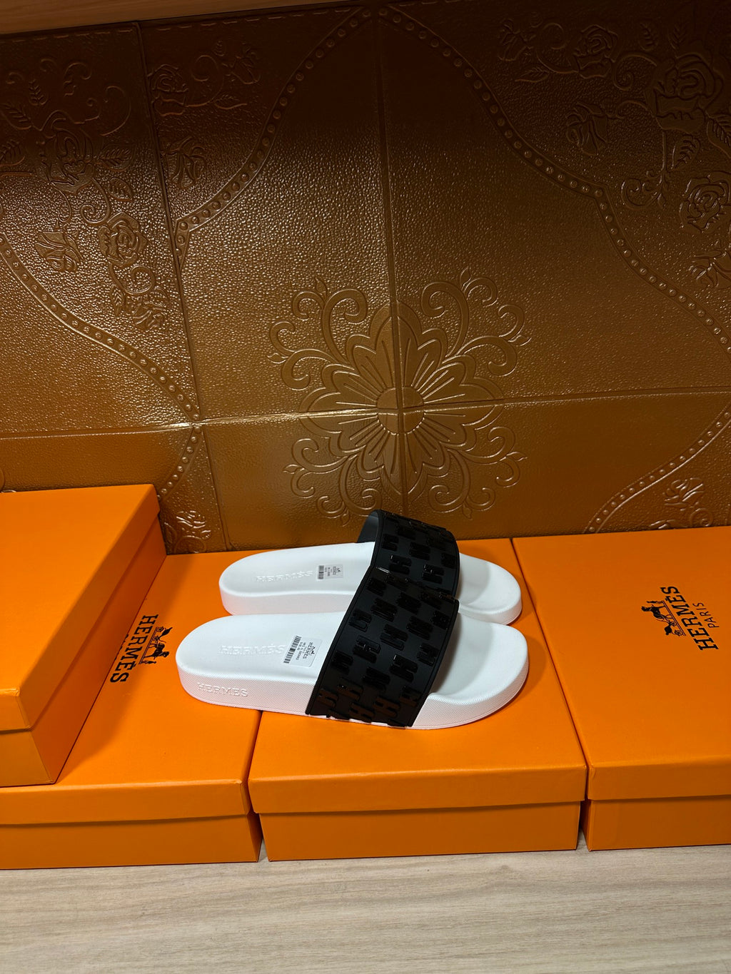 Hermes slide sandals on an orange box, white base with black patterned strap