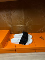 Hermes slide sandals on an orange box, white base with black patterned strap