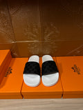 Hermes slide sandals with white footbed and black patterned strap, pair front view