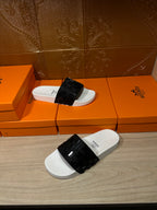 Hermes slide sandals with white footbeds and black patterned straps, pair view