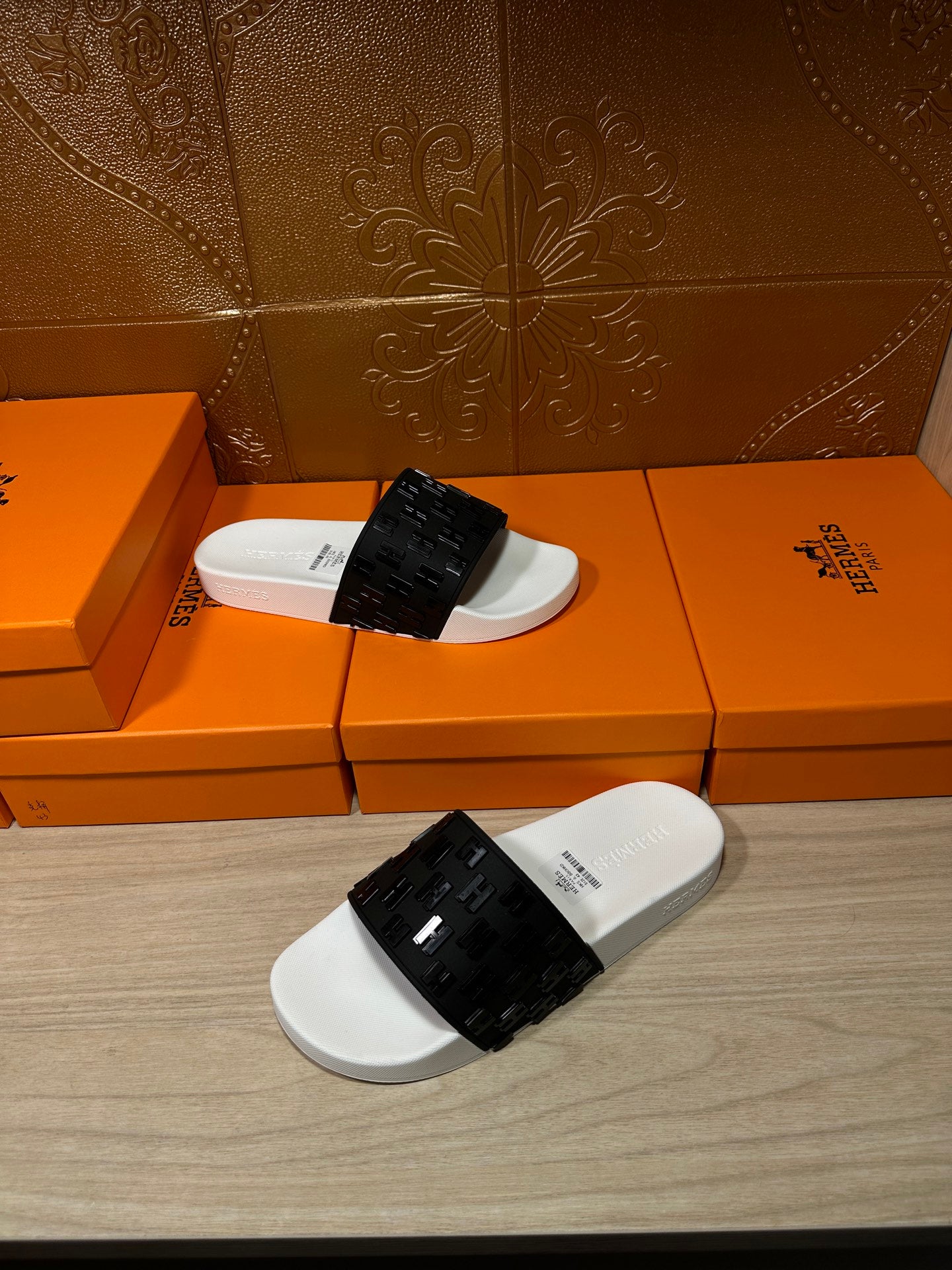 Hermes slide sandals with white footbeds and black patterned straps, pair view