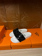 Hermes slide sandals with white footbed and black patterned strap, side angle