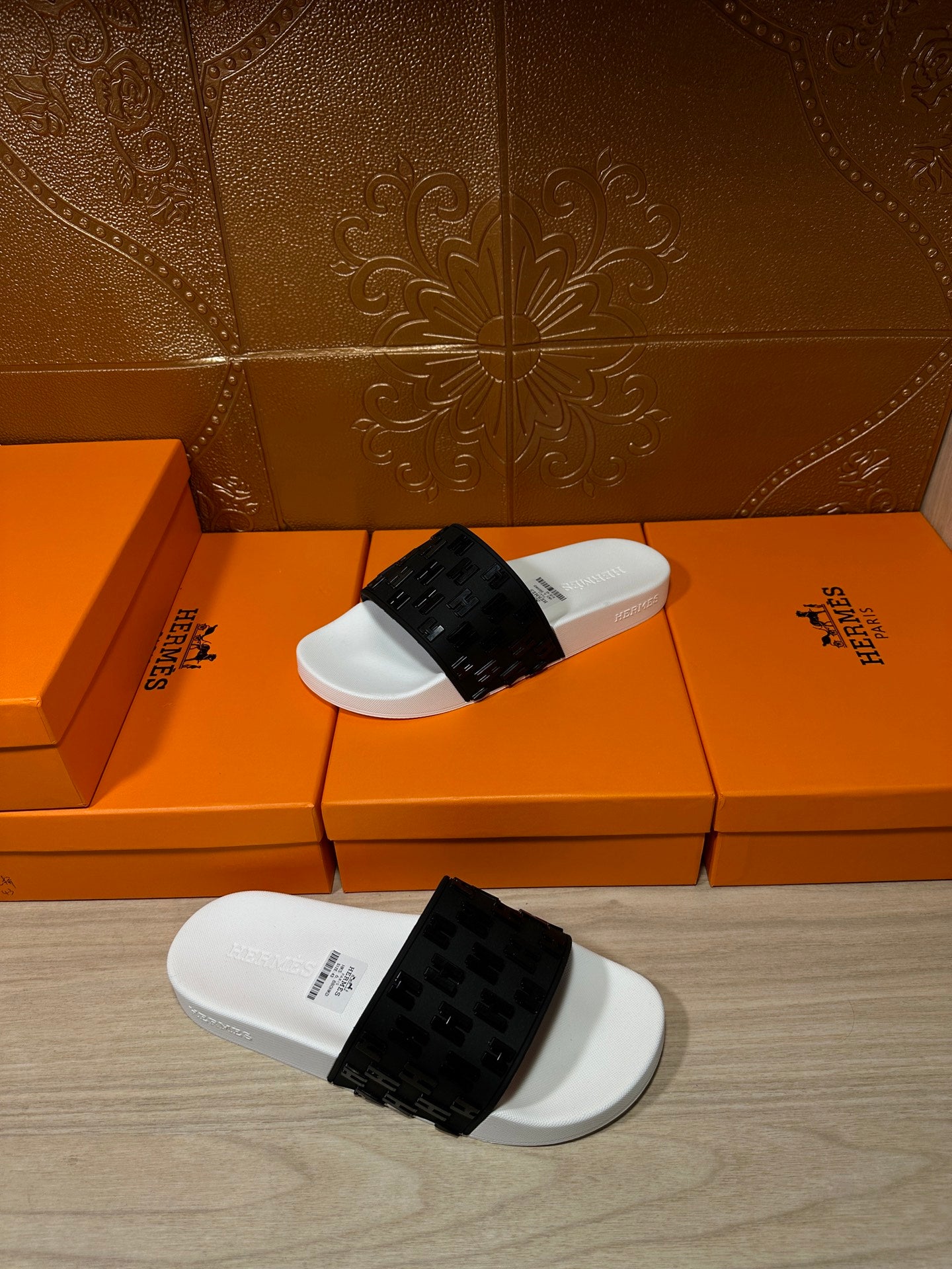 Hermes slide sandals laid on the floor, white footbed with black patterned strap