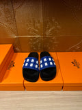 Hermes slide sandals with blue woven-style strap and black footbed, pair view