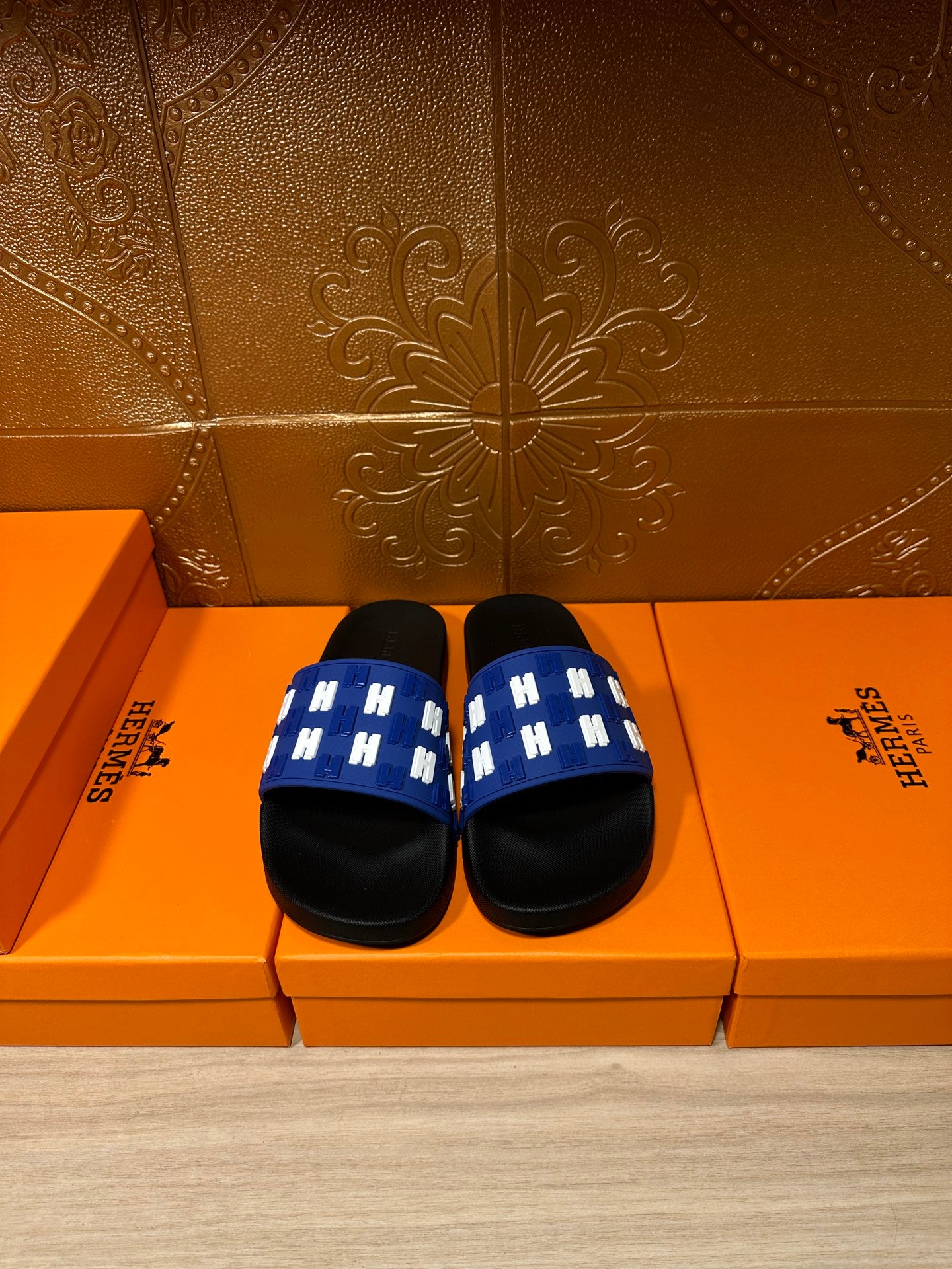 Hermes slide sandals with blue woven-style strap and black footbed, pair view