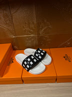 Hermes slide sandals, black strap with repeating H marks over white footbed