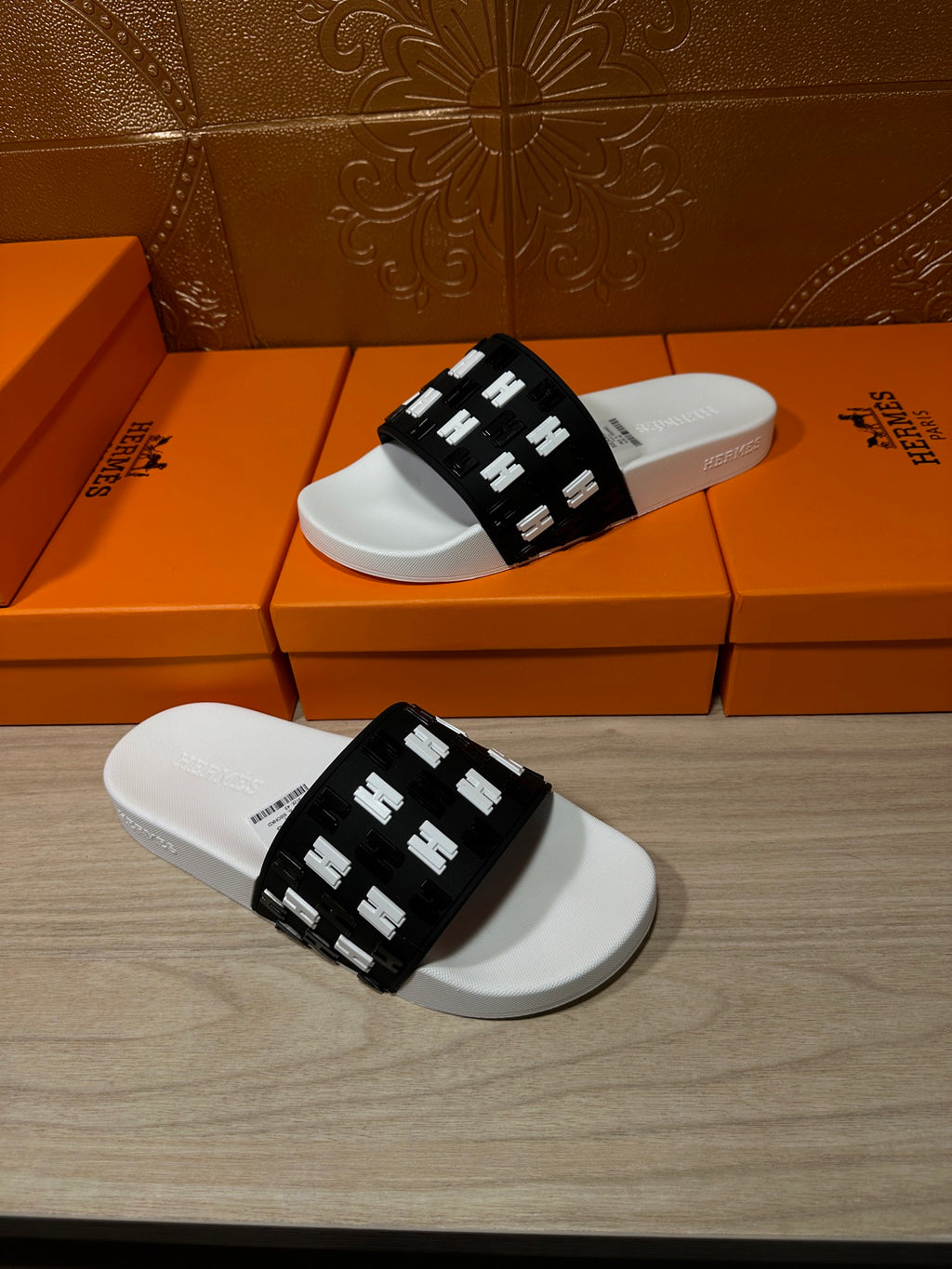 Hermes slide sandals on white footbeds with black H-pattern strap