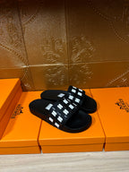 Black slide sandals with white patterned strap shown from above