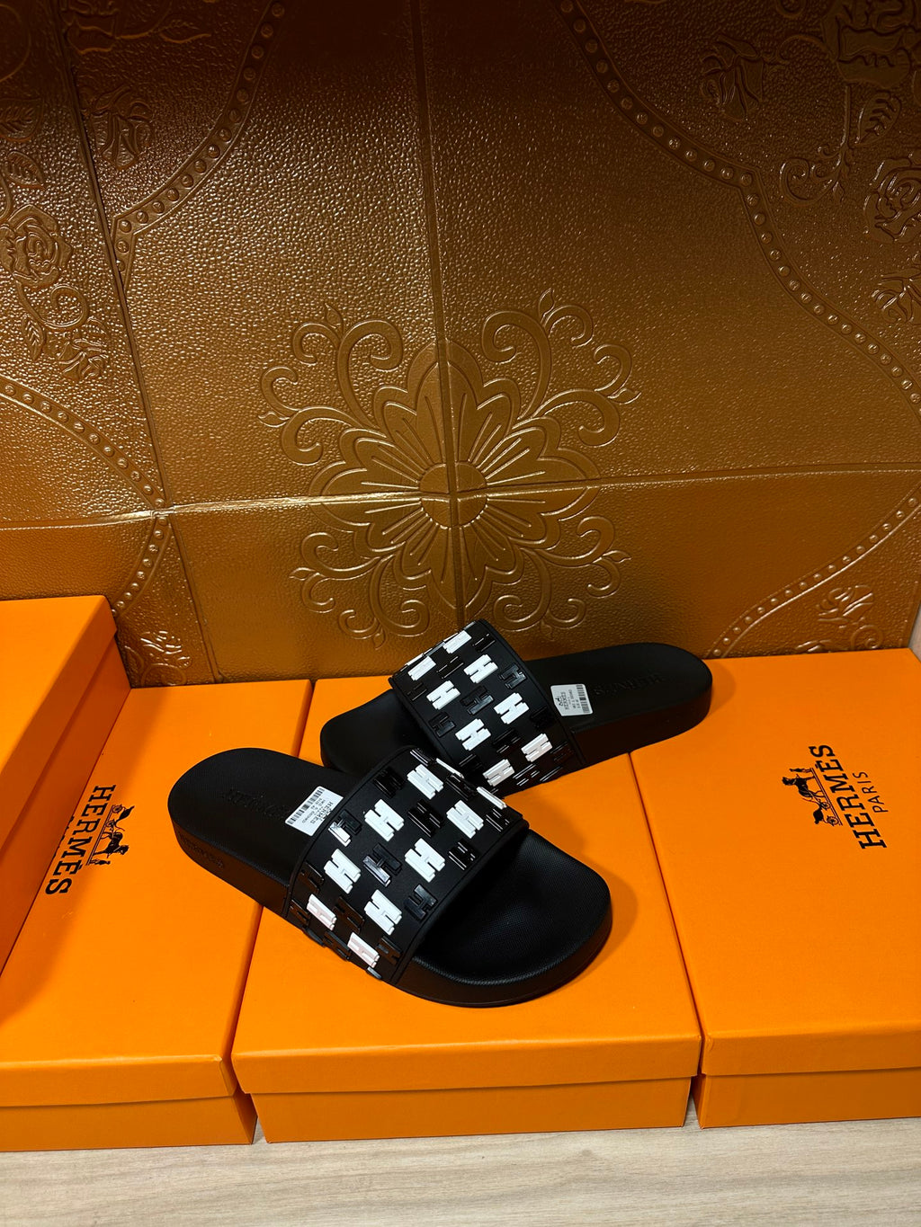 Black slide sandals with white patterned strap on the upper