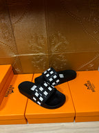 Black slide sandals with white patterned strap on the upper