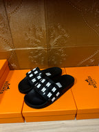 Black slide sandals with white geometric strap detail and open toe
