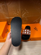 Hermes slide sandals, textured black outsole with repeating Hermes lettering