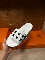 Hermes sandals, white slide held in hand with black H strap