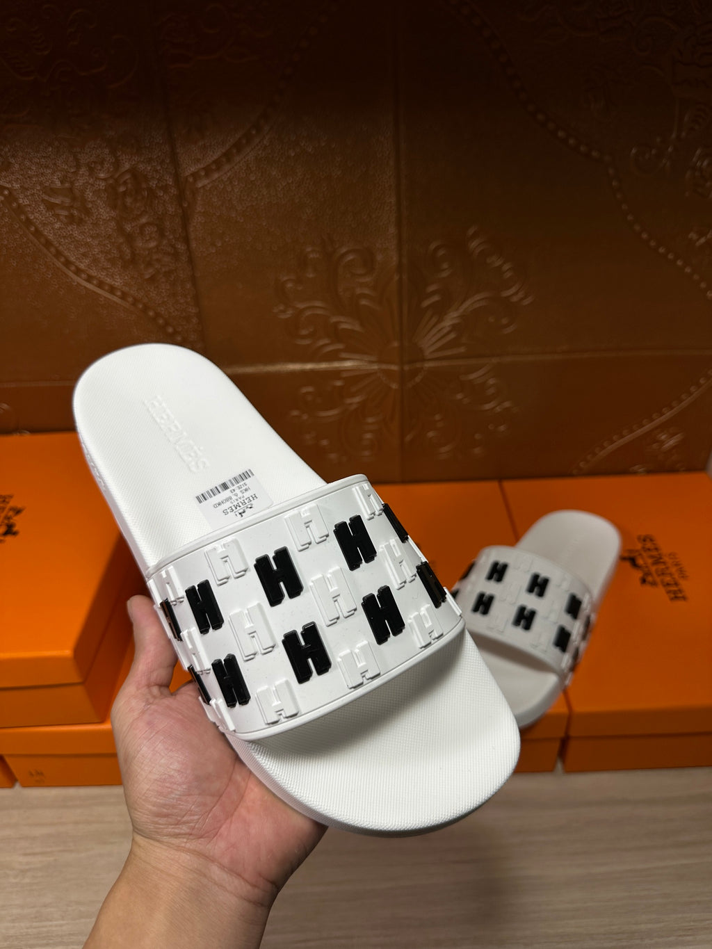 Hermes sandals, white slide in hand showing black H patterned strap