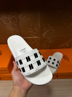 Hermes sandals, white slide in hand showing black H patterned strap
