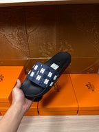Black slide sandals with navy strap, white H pattern; side angle