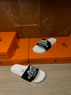 Hermes slide sandals with white footbed and black strap featuring Hermes Paris branding