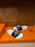 Hermes slide sandals, black strap with Hermes Paris logo over white footbed