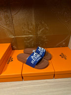 Brown slide sandals with blue Hermes Paris strap, front angle