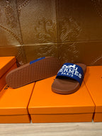 Brown slide sandal with textured sole and blue Hermes Paris strap