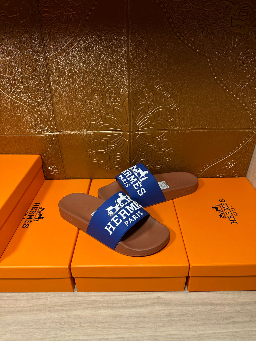 Brown slide sandals with blue Hermes Paris strap, angled view