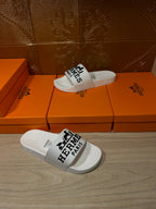 White slide sandals with black Hermes Paris logo strap