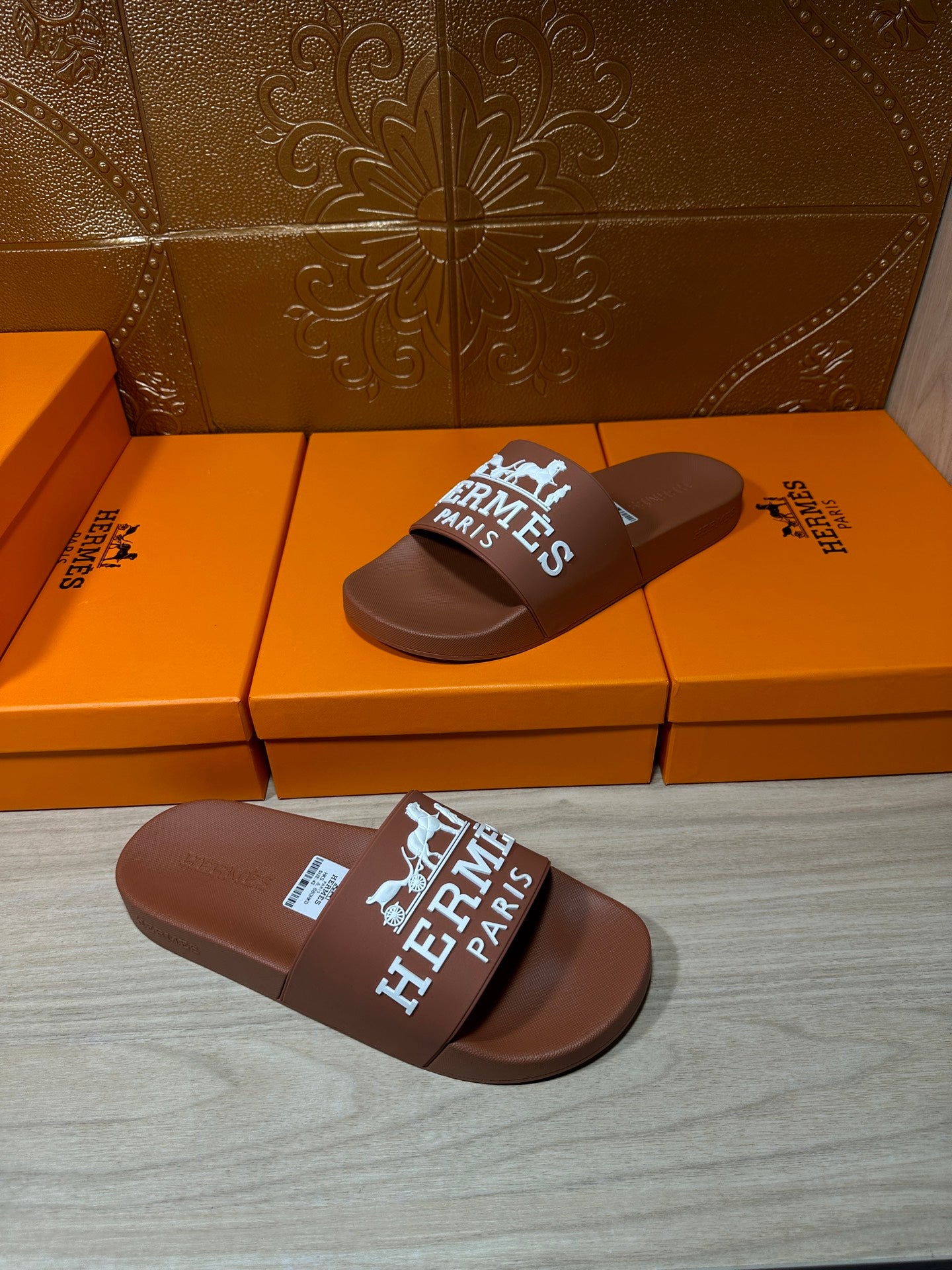 Brown slide sandal with white HERMES PARIS logo strap, angled