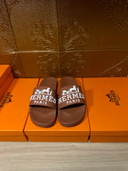 Brown slide sandals with white HERMES PARIS logo strap