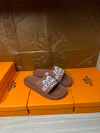 Brown slide sandals with white HERMES PARIS logo strap, single view
