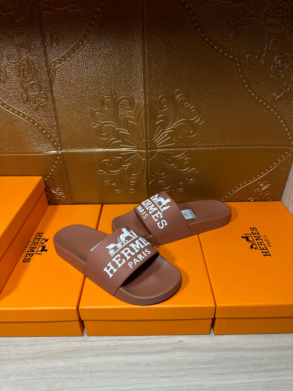 Brown slide sandals with white HERMES PARIS logo strap, front view