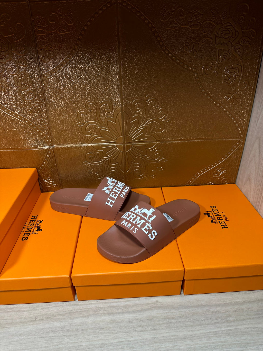 Pair of brown slide sandals with white HERMES PARIS logo strap