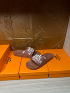 Pair of brown slide sandals with white HERMES PARIS logo strap