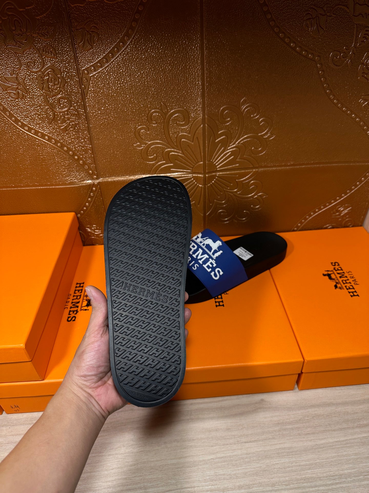 Black slide sandal outsole with textured tread, showing blue Hermes Paris strap.