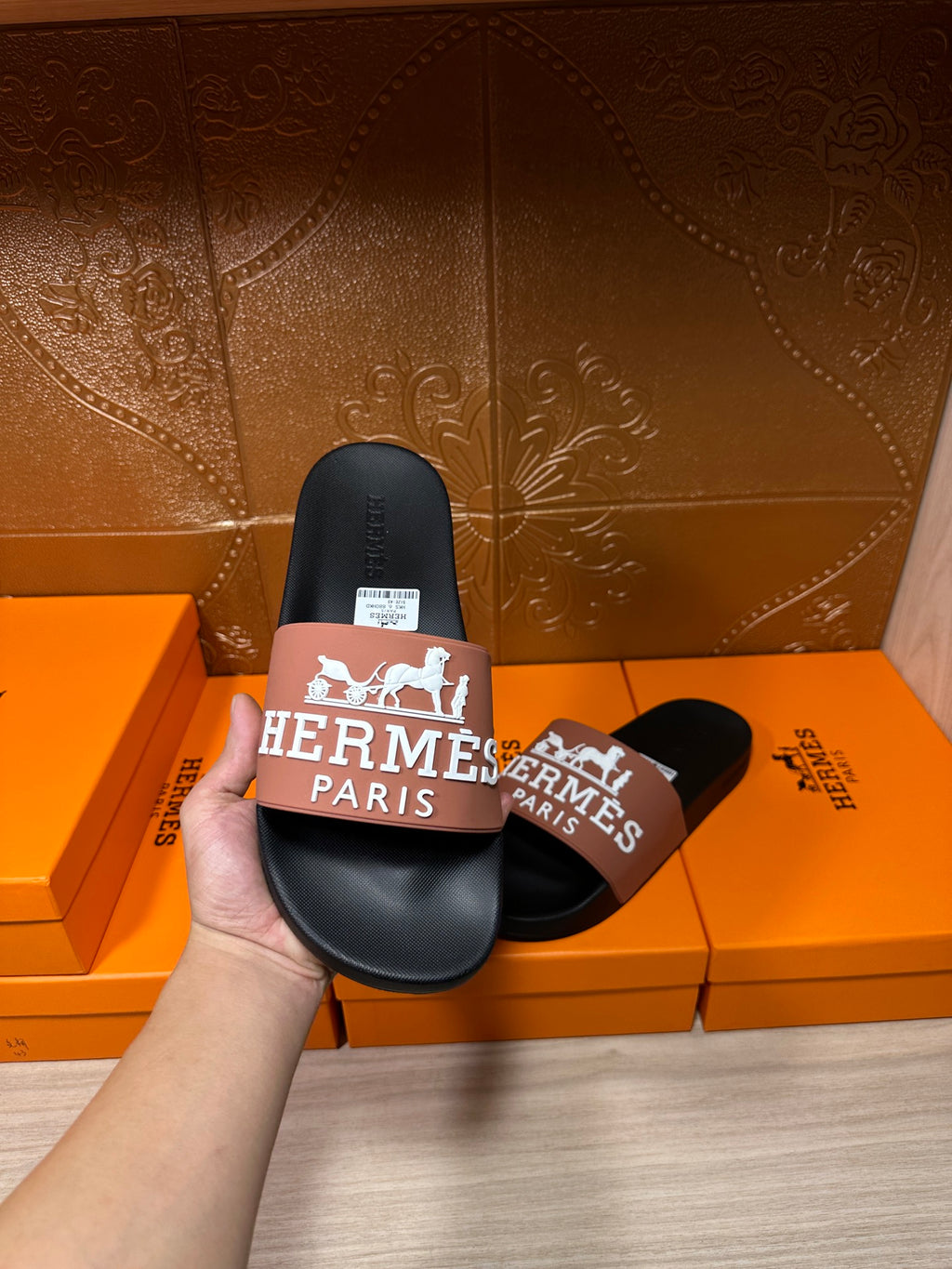 Black slide sandals held with tan Hermes Paris logo strap, view of footbed