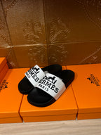 Hermes slide sandals with black soles and white "Hermes Paris" logo strap