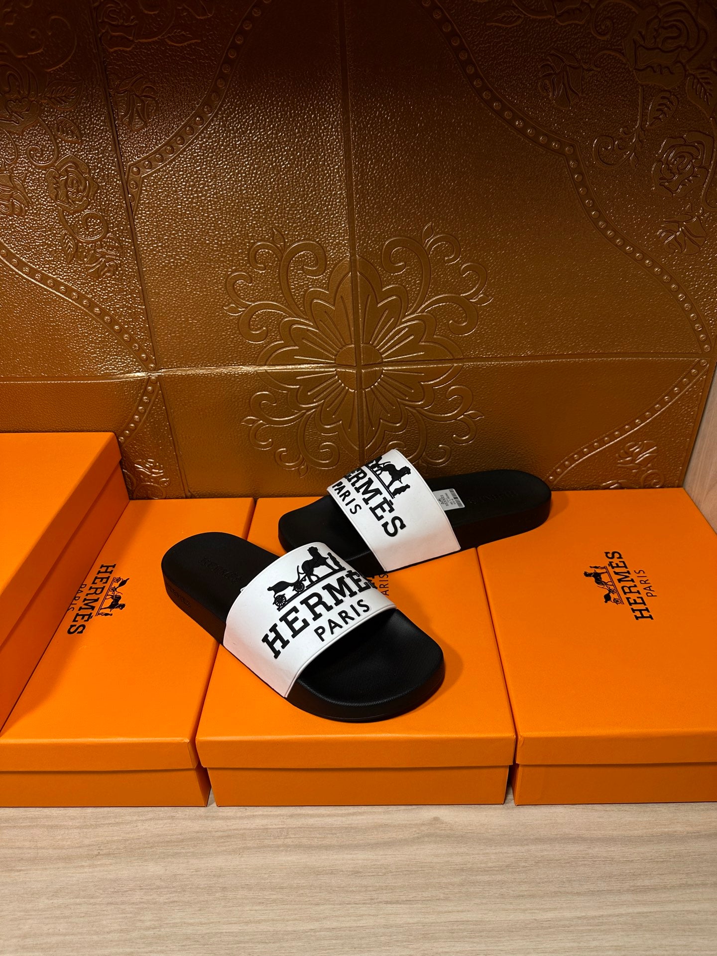 Hermes sandals featuring black slides with a white logo band on the top