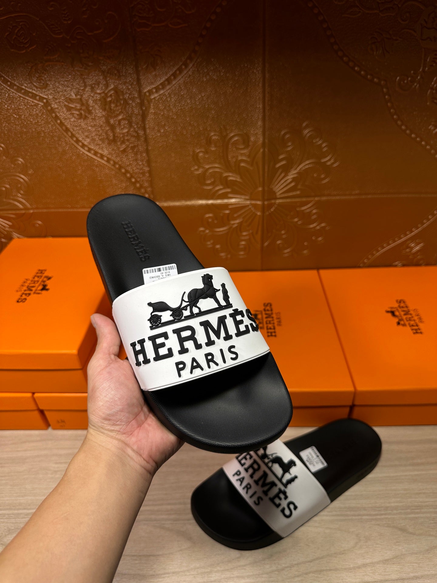 Hermes slide sandals held in hand: black footbed with white logo strap