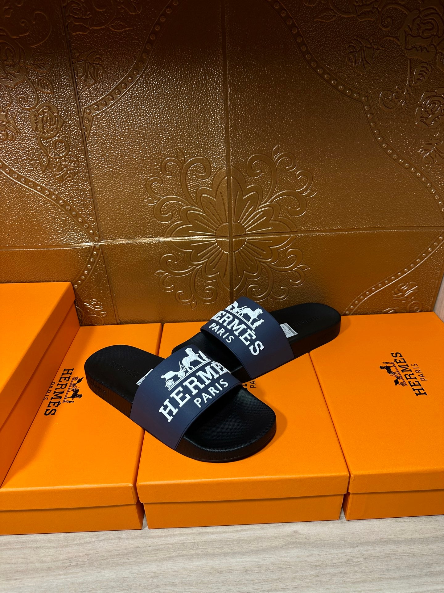 Black slide sandals with blue strap, white "Hermès Paris" lettering