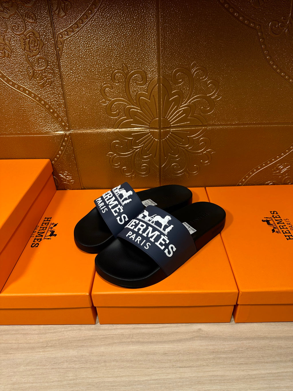 Black slide sandals with blue strap featuring "Hermès Paris" logo and text