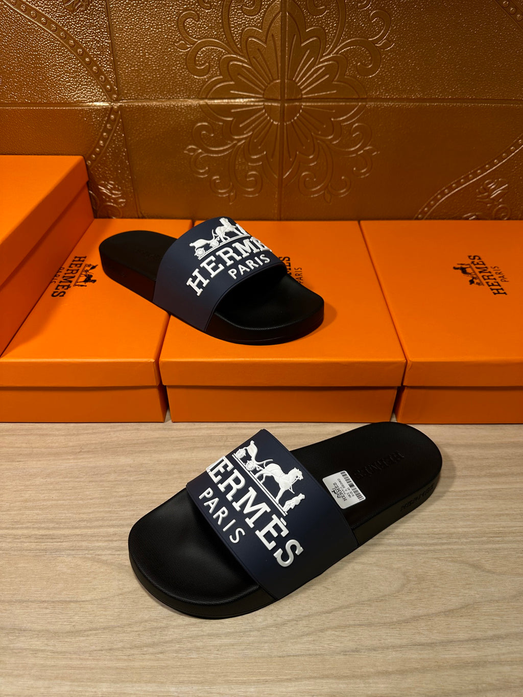 Black slide sandals with blue strap and large white "Hermès Paris" graphic