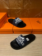 Black slide sandals with blue strap and large white "Hermès Paris" graphic