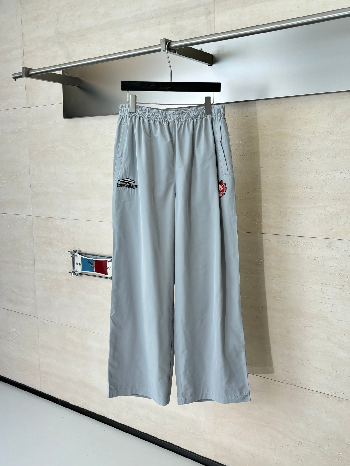 Light blue Balenciaga shorts with elastic waist and side crest patch, hanging on a hanger