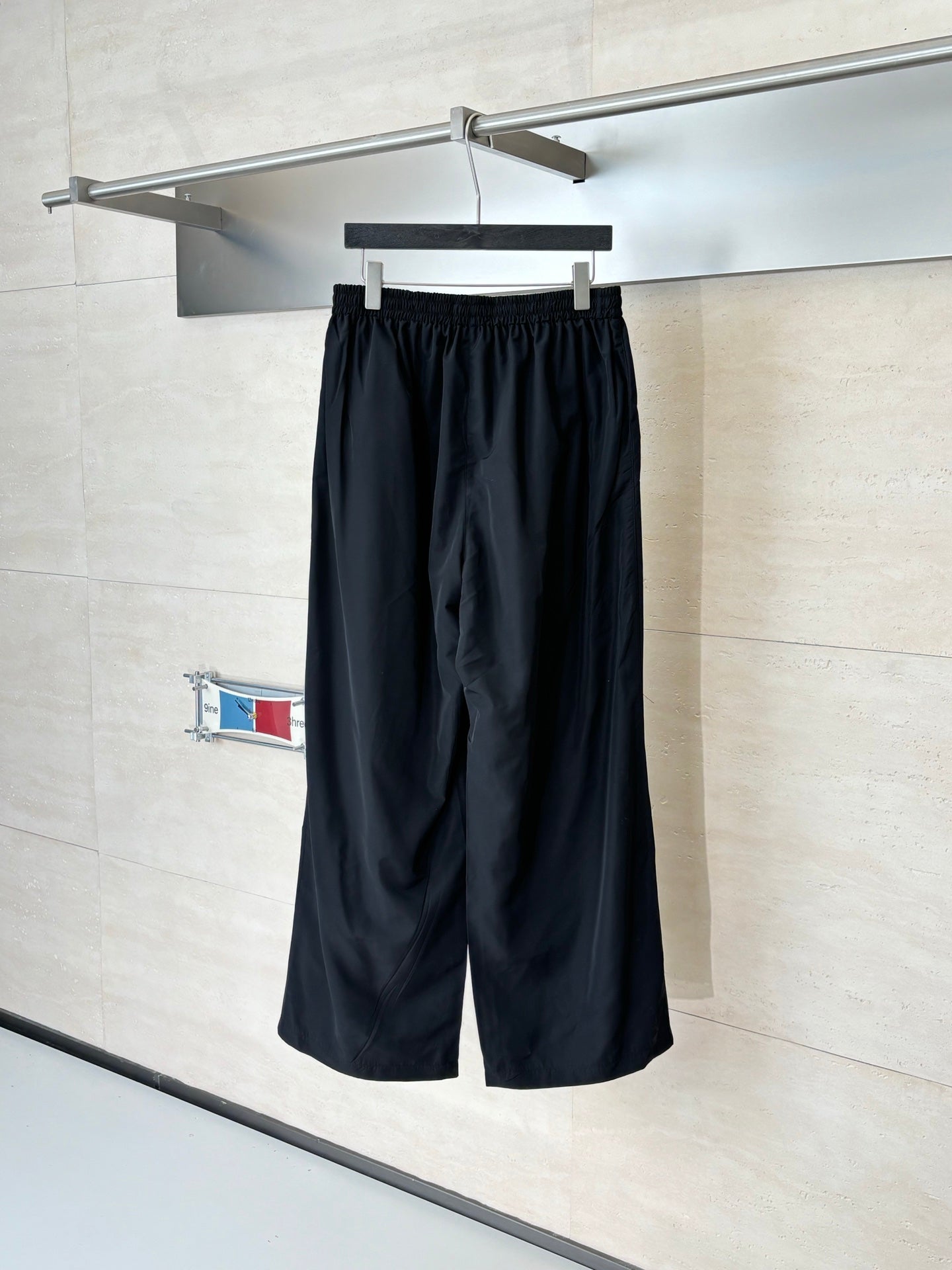 Black Balenciaga track pants on hanger, elastic waistband and wide straight legs