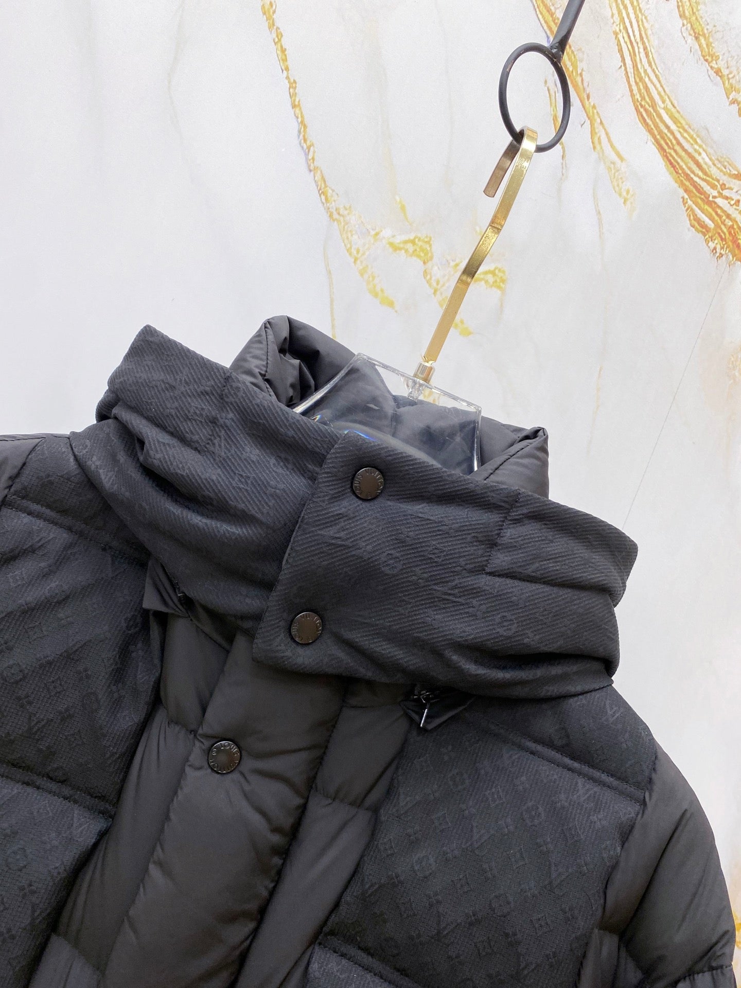 Dark gray puffer jacket collar detail with snap buttons and straps