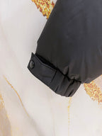 Dark gray puffer jacket cuff with snap strap detail