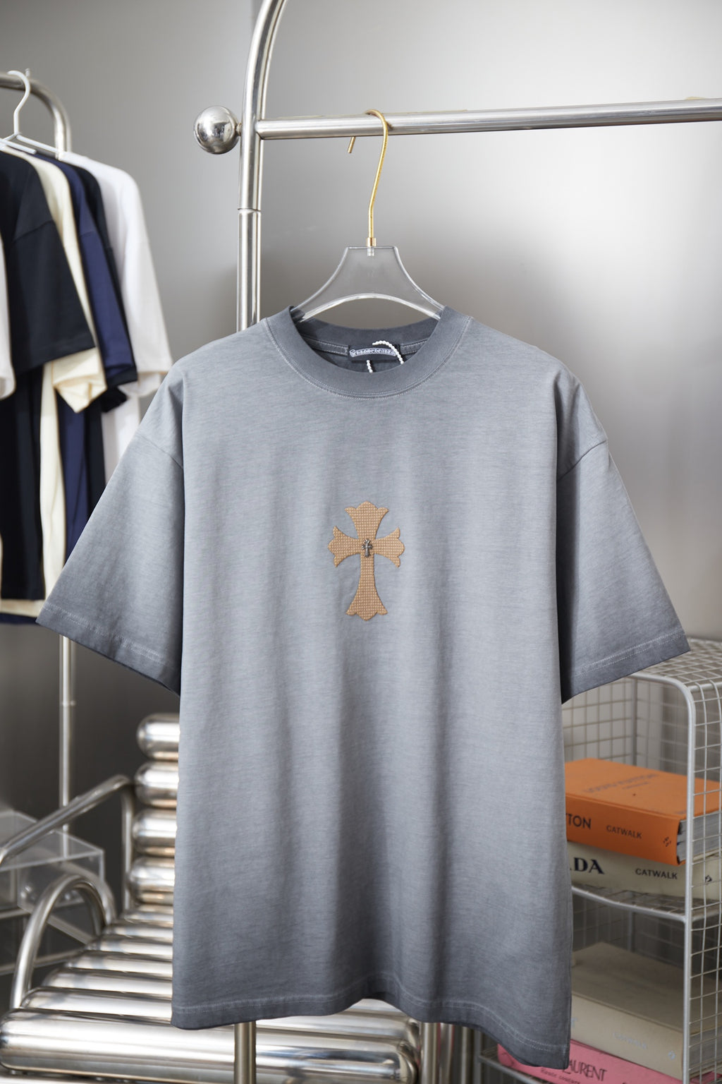 Light blue short-sleeve T-shirt with small cross graphic on the chest