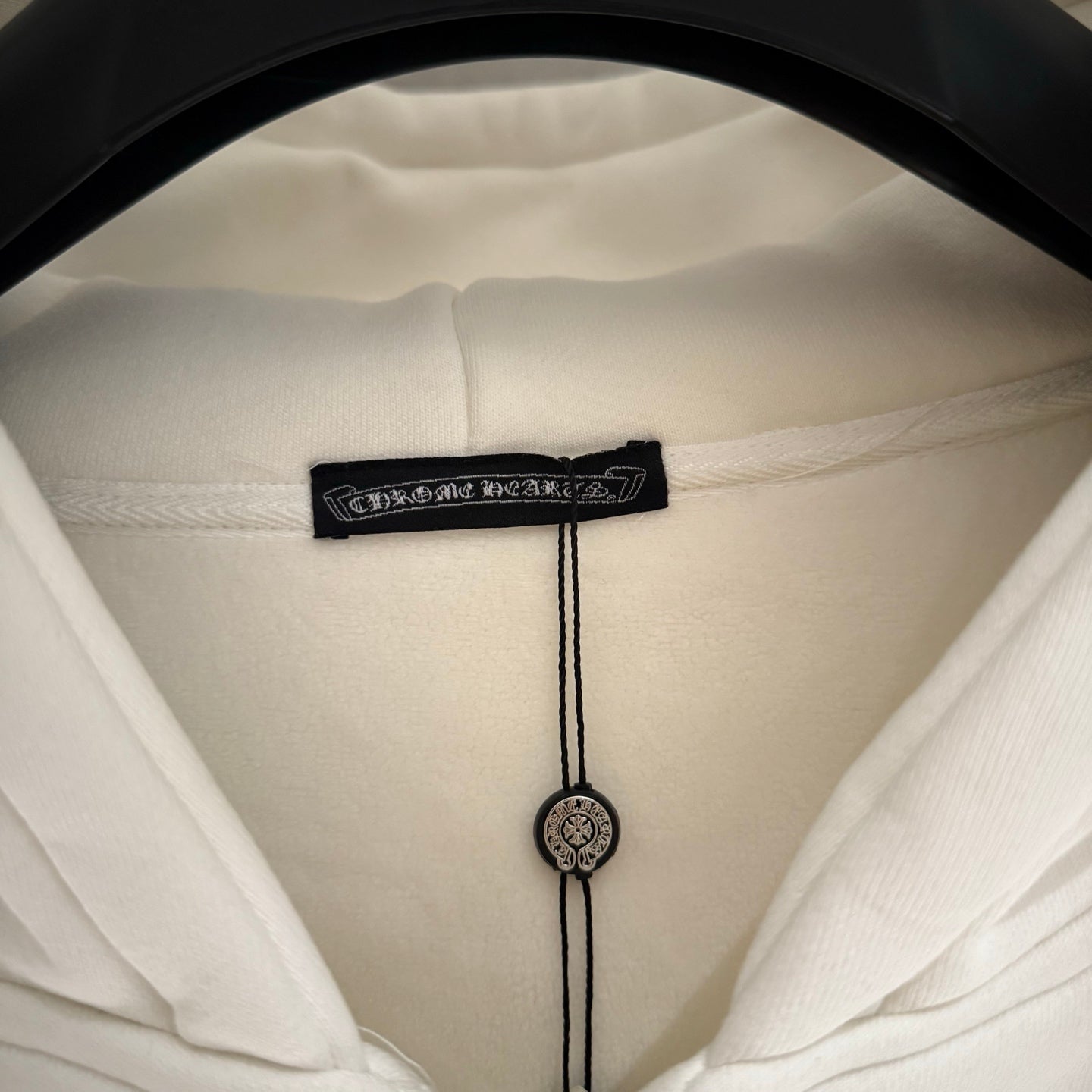 Close-up of white hoodie hood label with drawstring and cord end details