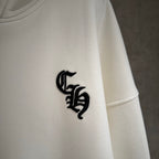 White hoodie sleeve with black embroidered emblem near the cuff