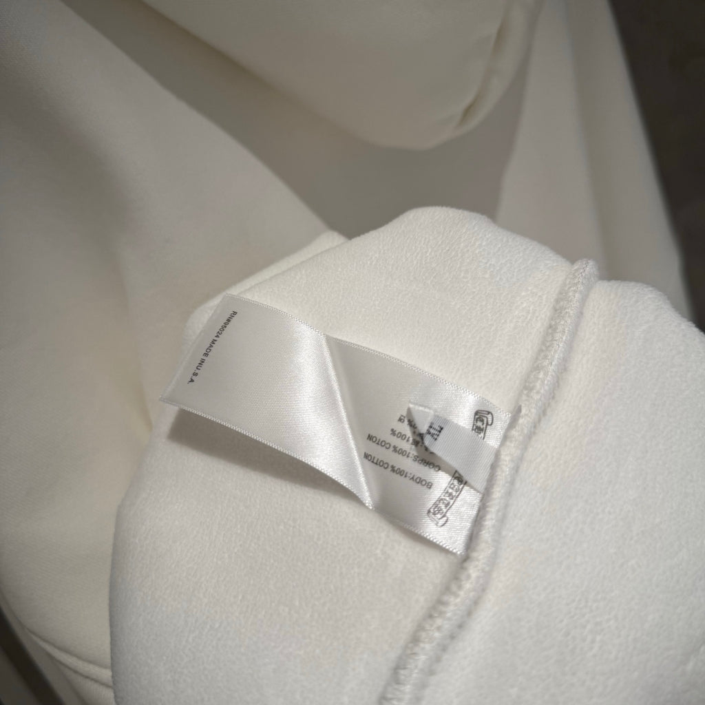 Close-up of white hoodie tag stitched near the zipper seam